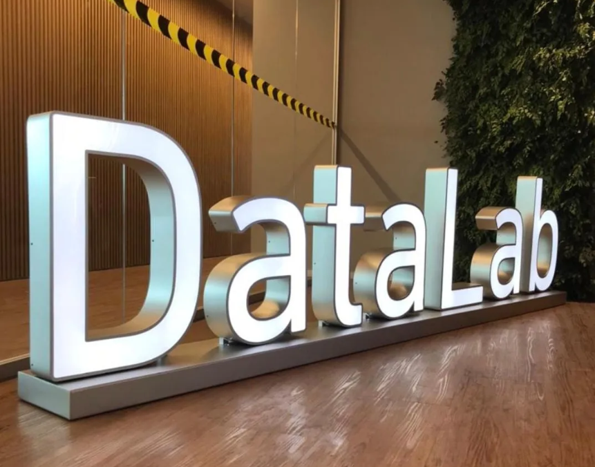 Letras caixa DataLab em inox escovado com acabamento metálico claro, instaladas em lobby corporativo