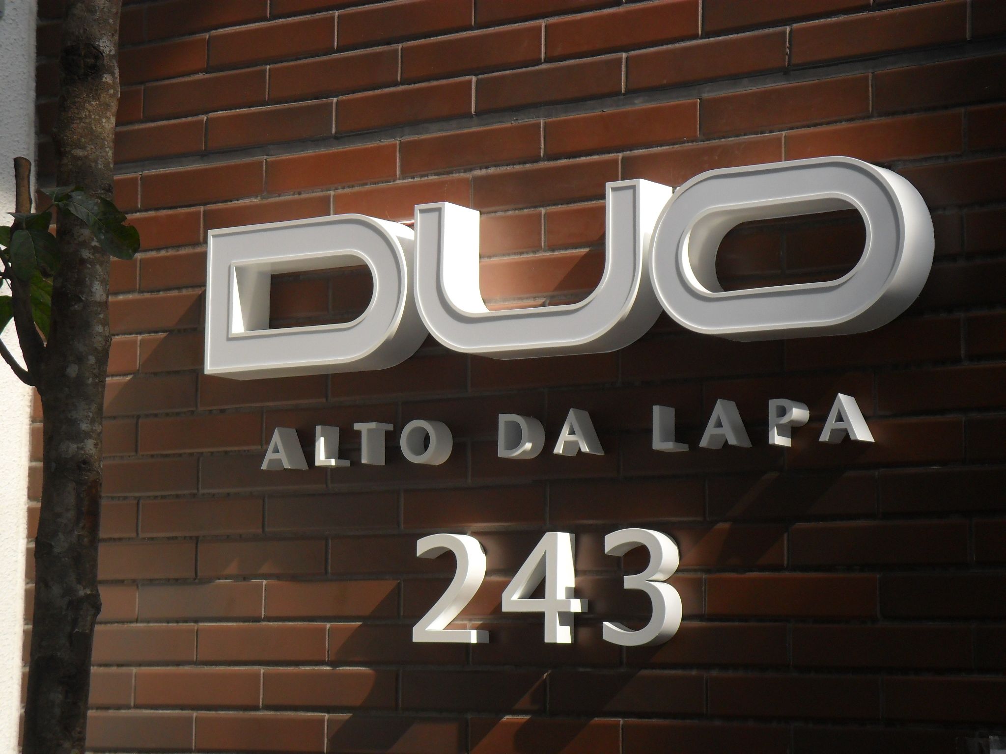 Letras caixa prateadas DUO sobre parede de tijolo aparente no Alto da Lapa, São Paulo
