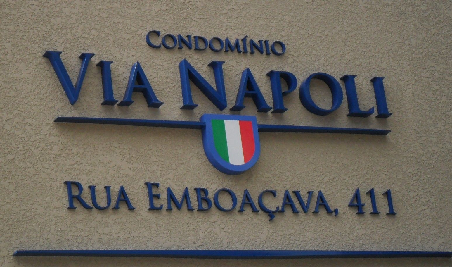 Letras caixa azuis com brasão italiano em fachada de Condomínio Via Napoli
